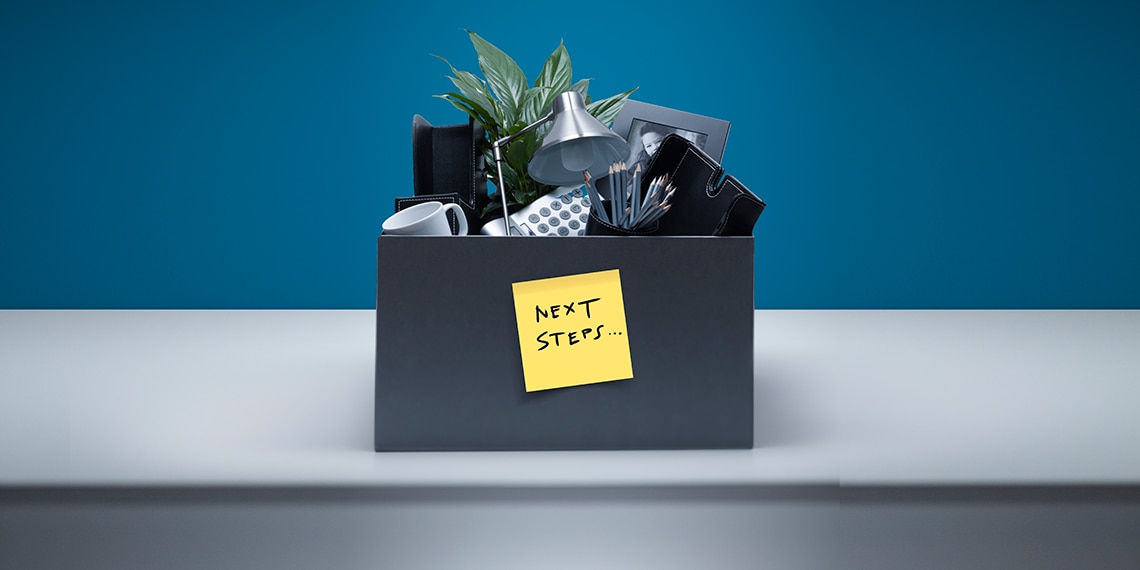 Box of items from an office with a sticky note that reads